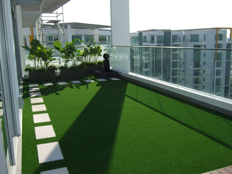 High balcony with artificial grass, planters and stepping stones.
